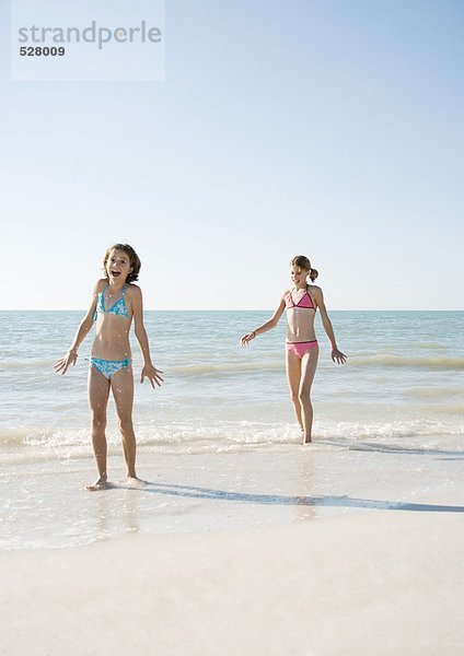 Zwei Mädchen  die am Strand spazieren gehen  eines mit offenem Mund.