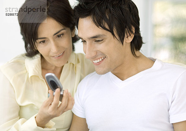 Junger Mann und Mutter beim Blick aufs Handy