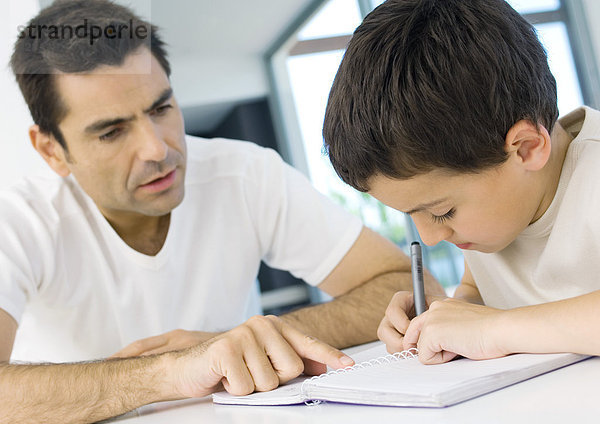 Junge  der mit Vaters Hilfe Hausaufgaben macht  abgeschnitten