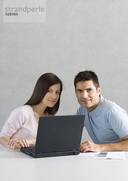 Paar mit Laptop  lächelnd in der Kamera
