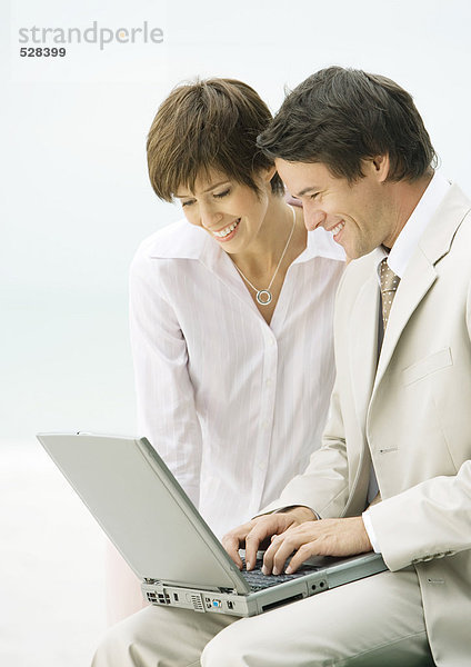 Geschäftsmann und Frau nutzen gemeinsam den Laptop