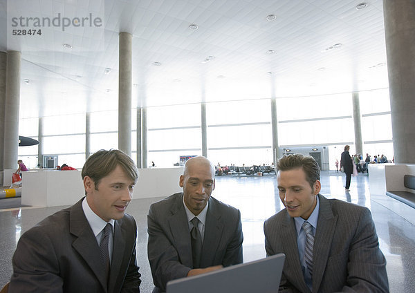 Drei Geschäftsleute mit Laptop am Flughafen