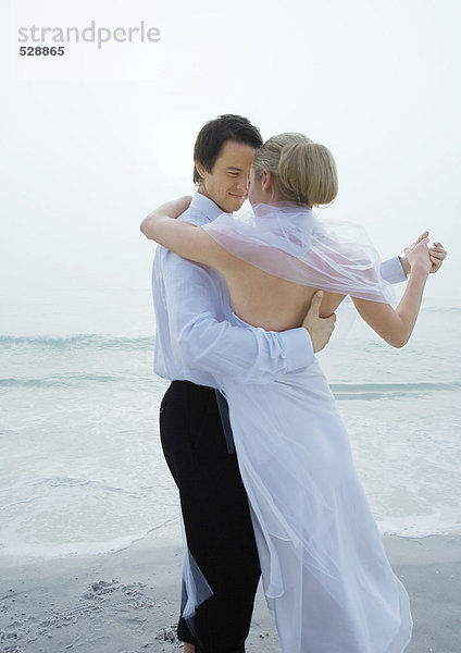 Braut und Bräutigam tanzen am Strand