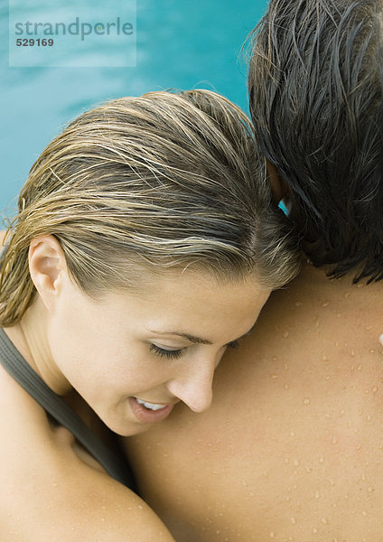 Paar in der Nähe des Swimmingpools  Frau liegt mit dem Kopf auf der Schulter des Mannes.