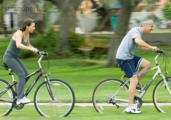 Reife Paare auf Fahrrädern  Seitenansicht
