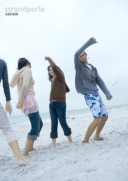 Junge erwachsene Freunde tanzen am Strand