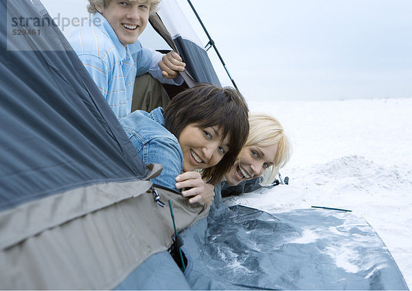 Junge erwachsene Freunde  die aus dem Zelt am Strand schauen.