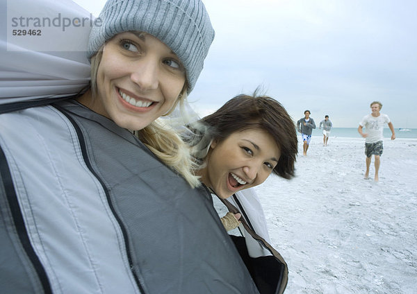 Junge erwachsene Freunde  die aus dem Zelt am Strand schauen.