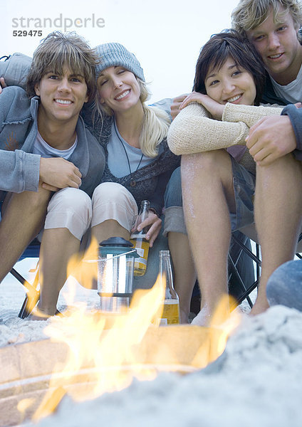 Junge erwachsene Freunde sitzen am Lagerfeuer