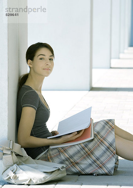 Studentin auf dem Boden sitzend  studierend