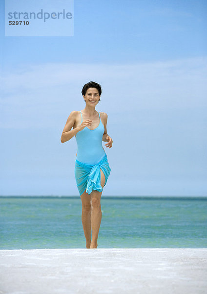 Frau läuft am Strand  Vorderansicht