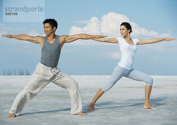 Mann und Frau beim Yoga am Strand