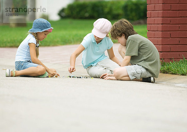 Kinder spielen Murmeln auf der Straße