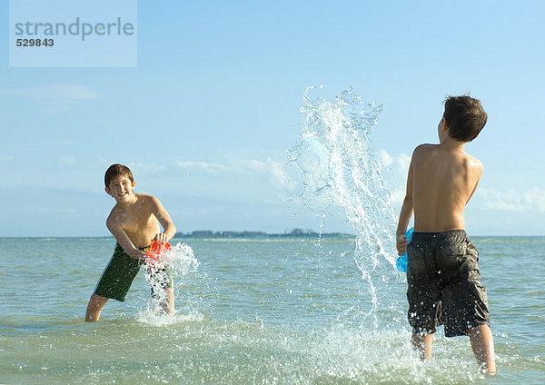 Zwei Jungen  die am Strand im Wasser planschen.