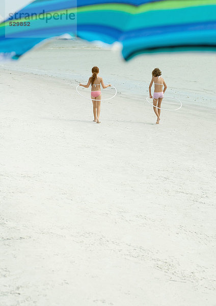 Kinder spielen mit Reifen am Strand