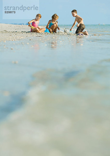Kinder spielen im Sand  am Strand