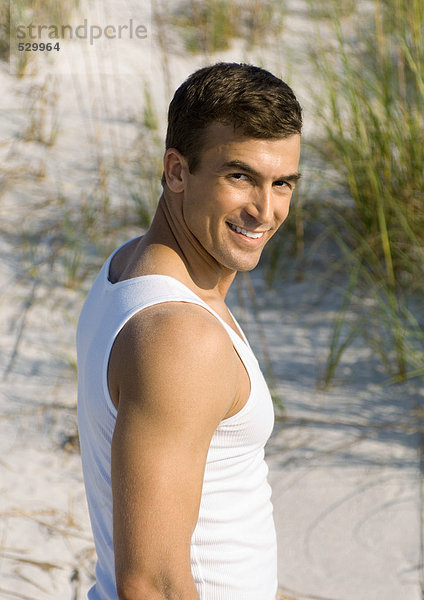 Mann am Strand  lächelnd vor der Kamera