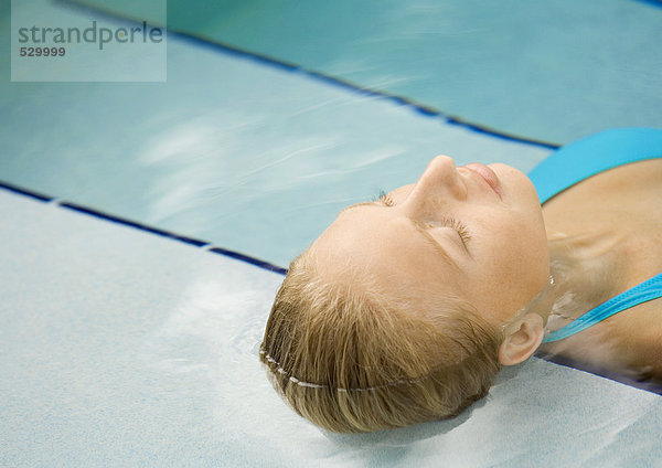 Frau im Pool liegend  Kopf auf der Treppe