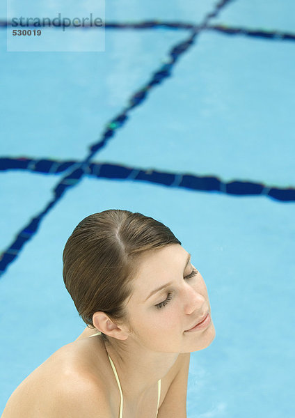 Frau am Pool  Augen geschlossen und lächelnd