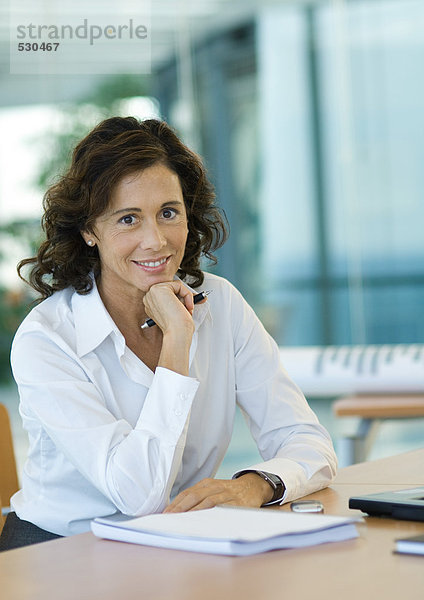 Geschäftsfrau am Schreibtisch sitzend  lächelnd vor der Kamera
