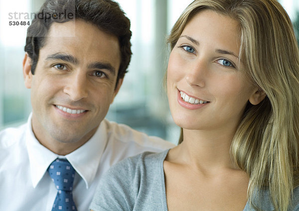 Männliche und weibliche Büroangestellte lächeln vor der Kamera