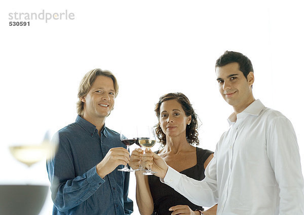 Drei Leute klirren an einem Glas Wein.