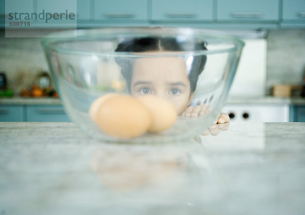 Mädchen schaut durch eine Schale mit Eiern