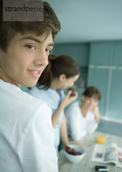 Teenager-Junge mit Familie in der Küche  über die Schulter schauend