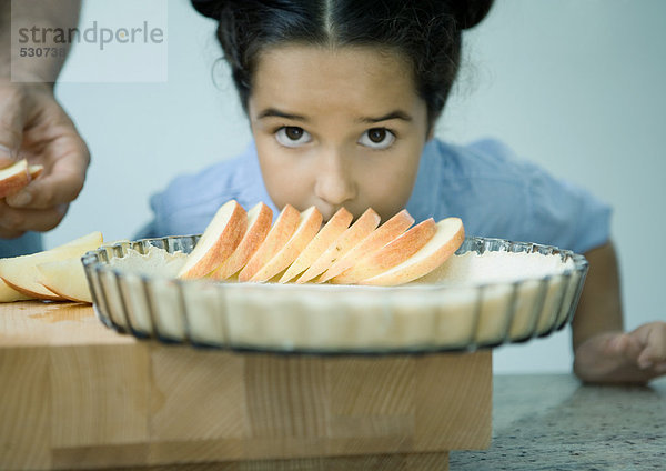 Mädchen lehnt sich über Apfelkuchenzubereitung