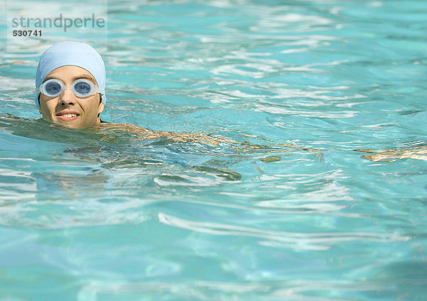 Person mit Badekappe und Schutzbrille im Pool