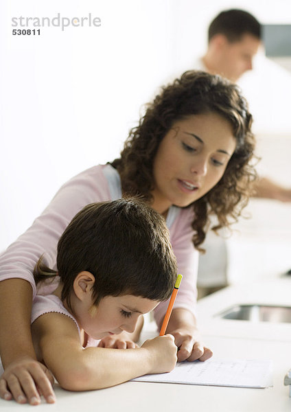 Mutter hilft Kind bei den Hausaufgaben