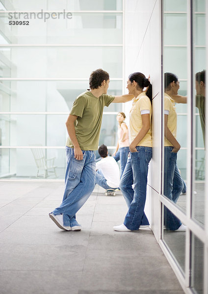 Teenager-Paar lehnt sich an die Wand