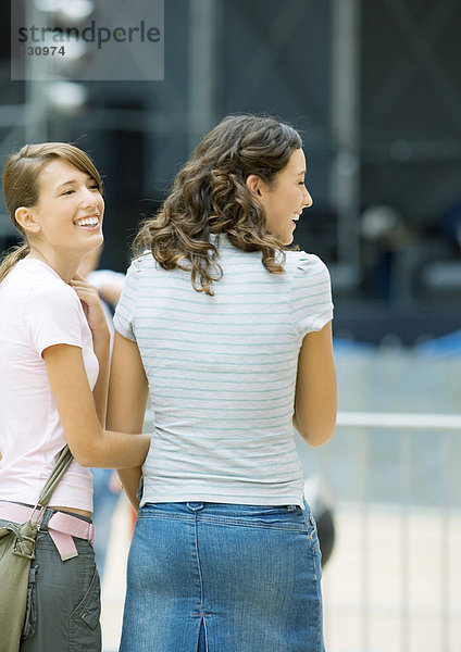 Zwei Teenagermädchen  die zusammen draußen stehen und lächeln.