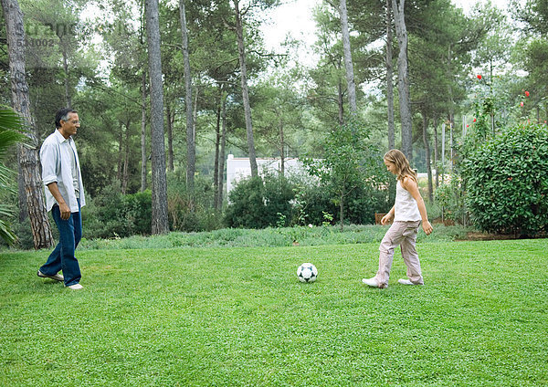 Erwachsener Mann spielt Fußball mit Enkelin