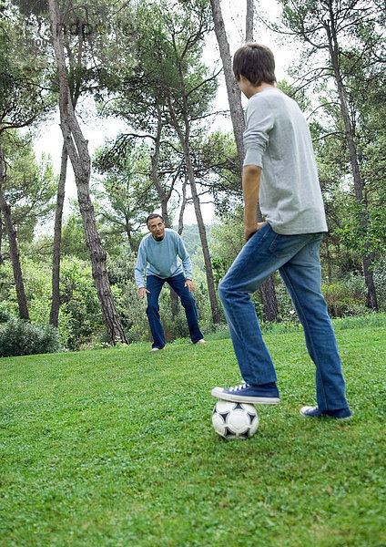 Erwachsener Mann und Teenager beim Fußballspielen