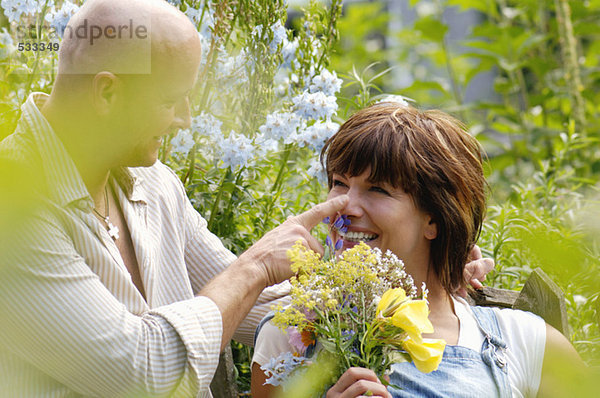 Paar im Garten mit einer Frau  die einen Blumenstrauß hält.