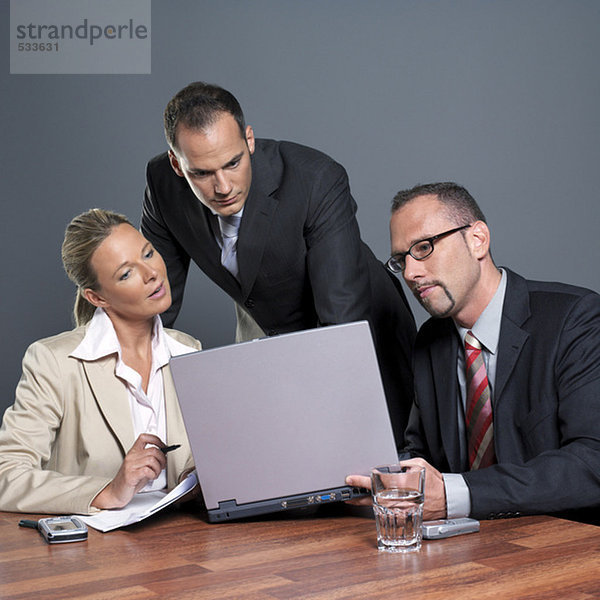 Geschäftsleute betrachten Laptop am Konferenztisch