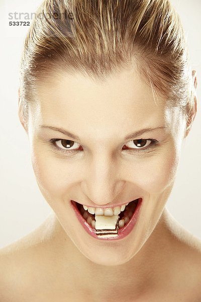 Junge Frau mit Süßigkeiten zwischen den Zähnen