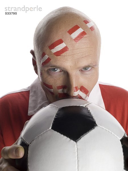 Mann mit österreichischer Flagge auf Gesicht gemalt  Fußball küssen  Portrait  Nahaufnahme