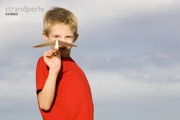 Junge (10-12) hält Papierflugzeug