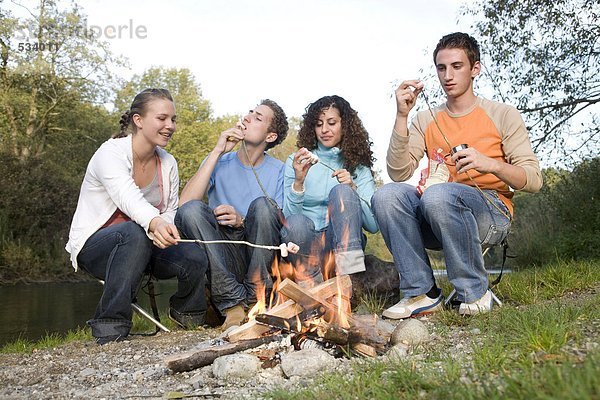 Teenager sitzen um das Feuer herum