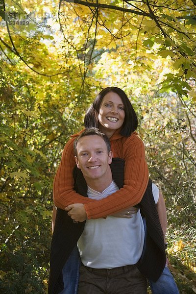 Mann mit Frau Huckepack  lächelnd  Portrait