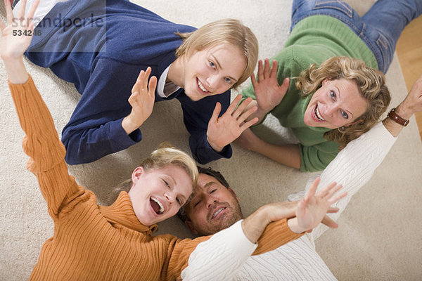 Familie auf dem Boden liegend im Wohnzimmer  lächelnd  erhöhte Aussicht