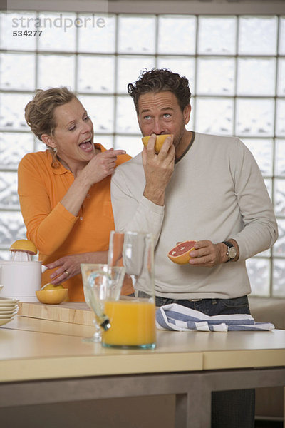 Mature couple in kitchen  Man eating grapefruit