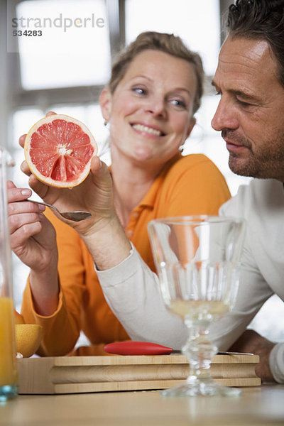 Reife Paare essen Grapefruit in der Küche  Frau lächelt