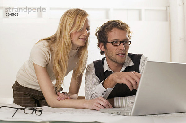 Junger Mann und Frau mit Laptop  lächelnd