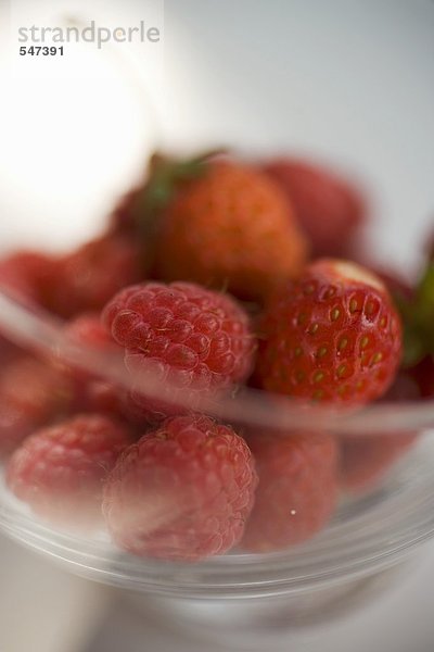Frische Himbeeren und Erdbeeren in einem Glasschälchen