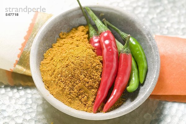 Currypulver und Chilischoten in Schale