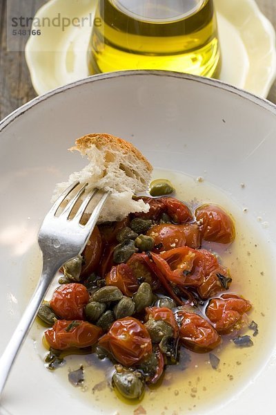 Gebratene Tomaten mit Kapern  Weissbrot auf Gabel  Olivenöl