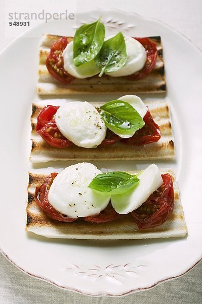Drei Toasts mit Tomaten  Mozzarella und Basilikum